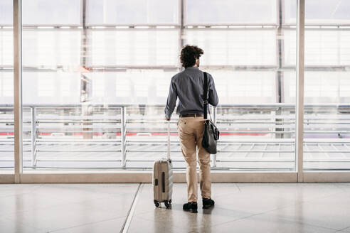 Businessman with luggage standing at station - EBBF07764