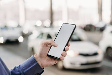 Hand eines Geschäftsmannes, der auf der Straße ein Smartphone benutzt - EBBF07815