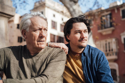 Nachdenklicher älterer Mann sitzt mit seinem Sohn vor einem Gebäude - JOSEF16300