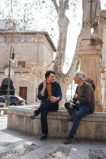 Man talking with father sitting on wall - JOSEF16301