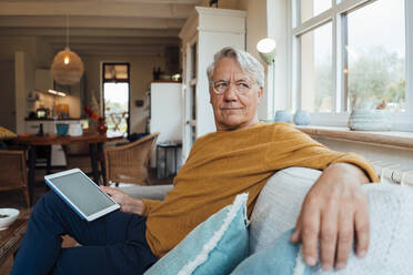 Älterer Mann sitzt mit Tablet-PC auf dem Sofa im heimischen Wohnzimmer - JOSEF16421