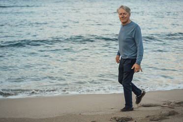 Lächelnder älterer Mann, der am Strand spazieren geht - JOSEF16467