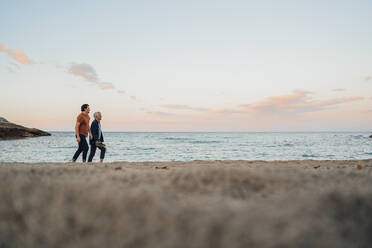 Father and son walking together on beach at sunset - JOSEF16493