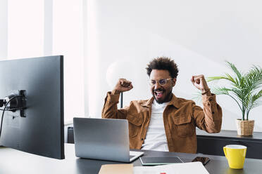 Successful businessman working on laptop at desk in office - PNAF04878