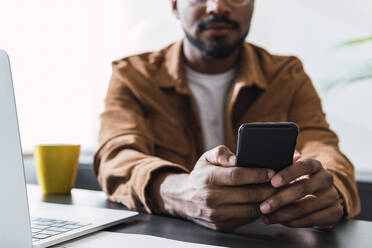 Geschäftsmann mit Smartphone am Schreibtisch im Büro - PNAF04894