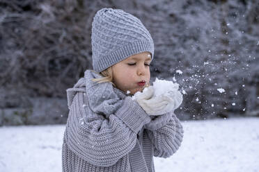 Verspieltes Mädchen in warmer Kleidung beim Schneeräumen - LBF03704