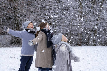 Cheerful brother and sisters in warm clothing enjoying snow - LBF03714