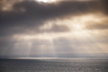 Sunbeams falling on sea through storm clouds at sunset - SMAF02518