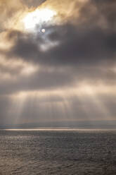 Sunlight falling on seascape through storm clouds at sunset - SMAF02519