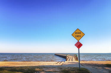 Road sign with Road Ends text in front of pier, Lake Huron, Michigan, USA - SMAF02530