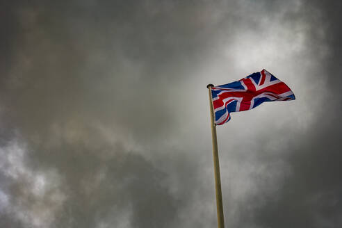 Union Jack flag waving below storm clouds - SMAF02536