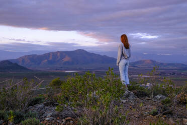 Young woman standing on rock at sunset - LBF03716