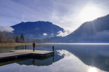 Österreich, Niederösterreich, Lunz am See, Mann bewundert Sonnenaufgang über dem Lunzer See von der Kante des Stegs - LBF03733