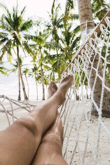 Mann sitzt in Hängematte am Strand, Bohol, Philippinen - PNAF04947