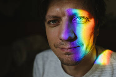 Smiling man with rainbow light on face - TYF00688
