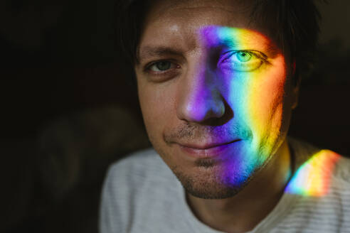 Lächelnder Mann mit Regenbogenlicht im Gesicht - TYF00688