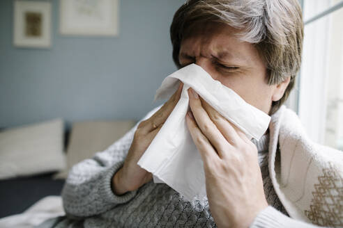Sick man blowing nose at home - TYF00693