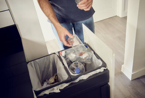 Man recycling plastic bottles at home - PWF00692