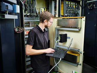 Techniker mit Laptop an einer Maschine in einer modernen Fabrik - CVF02279