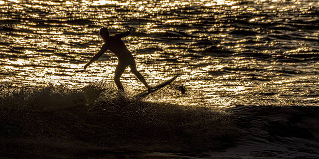 Silhouette Mann beim Surfen auf dem Meer bei Sonnenuntergang, Pembrokeshire, Wales - ALRF01937