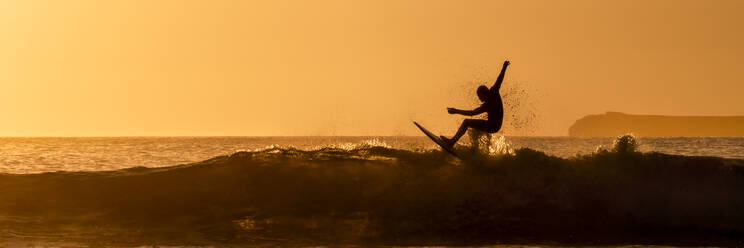 Silhouette Mann beim Surfen im Meer bei Sonnenuntergang, Pembrokeshire, Wales - ALRF01942