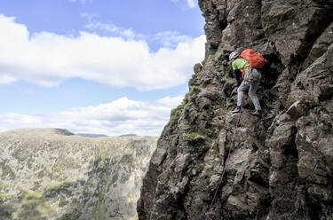 Mann mit Rucksack beim Klettern auf einem Berg, Lake District, England - ALRF01961