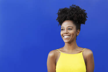 Nachdenkliche Frau mit Afrofrisur vor blauem Hintergrund - LMCF00020