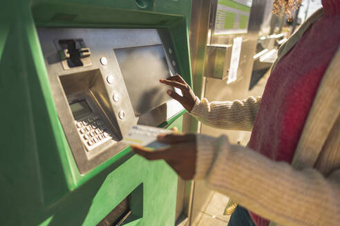 Junge Frau mit Kreditkarte an einem Geldautomaten - JCCMF09072