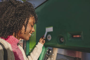 Lächelnde Frau mit Kreditkarte am Geldautomaten - JCCMF09074