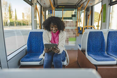 Glückliche Frau mit Tablet-PC in der Straßenbahn - JCCMF09081