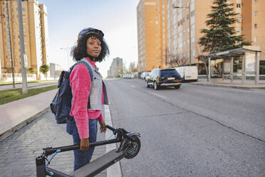 Lächelnde Frau mit Elektro-Scooter auf der Straße stehend - JCCMF09110