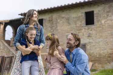 Fröhliche Familie, die gemeinsam vor dem Haus genießt - EIF04220