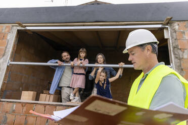 Bauarbeiter mit Familie durch ein Fenster auf der Baustelle gesehen - EIF04252