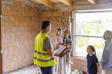 Architekt im Gespräch mit Familie auf der Baustelle - EIF04253