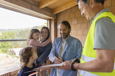 Mature man with family signing document at construction site - EIF04256