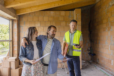 Bauunternehmer mit reifem Paar im Gespräch auf der Baustelle - EIF04258