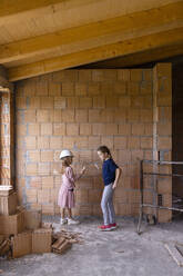 Mädchen mit Kreidezeichnung auf einer Backsteinmauer auf einer Baustelle - EIF04263