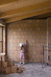 Mädchen mit Kreidezeichnung auf einer Backsteinmauer auf einer Baustelle - EIF04264