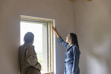 Älteres Paar steht am Fenster und diskutiert zu Hause - EIF04291