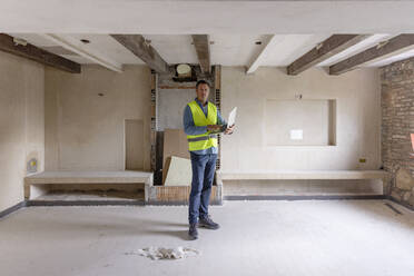 Contractor with laptop standing at construction site - EIF04306