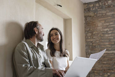 Happy woman and man sitting with laptop at home - EIF04310