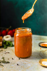 Fresh homemade tomato sauce in jar kept on table - FLMF00888