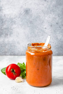 Glas mit selbstgemachter Tomatensauce auf dem Tisch - FLMF00902