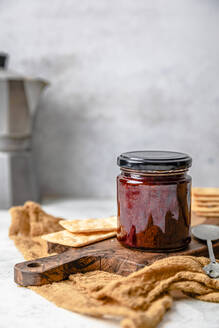 Homemade strawberry jam in jar with crackers - FLMF00929