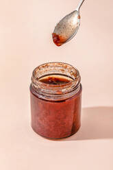 Homemade strawberry jam with spoon over peach background - FLMF00935