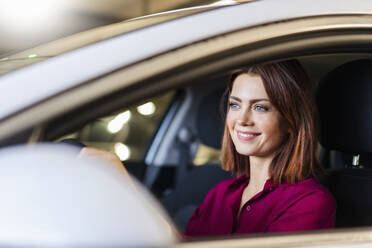 Smiling redheaded businesswoman driving car - DIGF19703