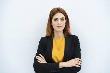 Confident businesswoman standing with arms crossed against white background - DIGF19713