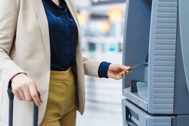 Hand einer Geschäftsfrau, die eine Kreditkarte am Geldautomaten benutzt - DIGF19748