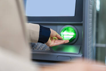 Hand einer Geschäftsfrau beim Einführen einer Kreditkarte in einen Geldautomaten - DIGF19752