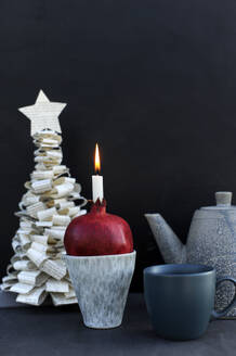 DIY Christmas tree made of book pages and candle burning inside pomegranate - GISF00958